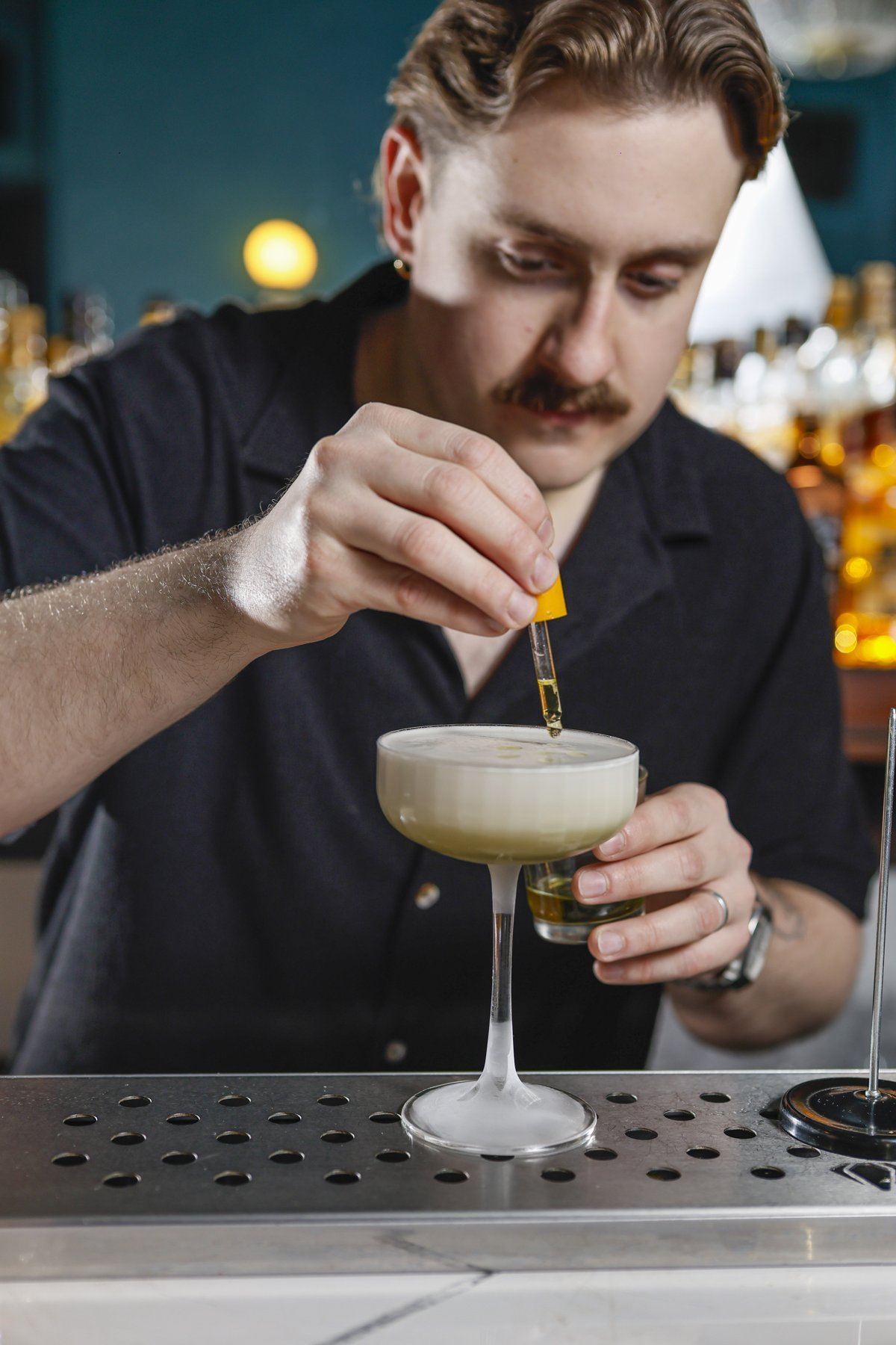Bartender de Noble Bar termina un cóctel con un gotero.